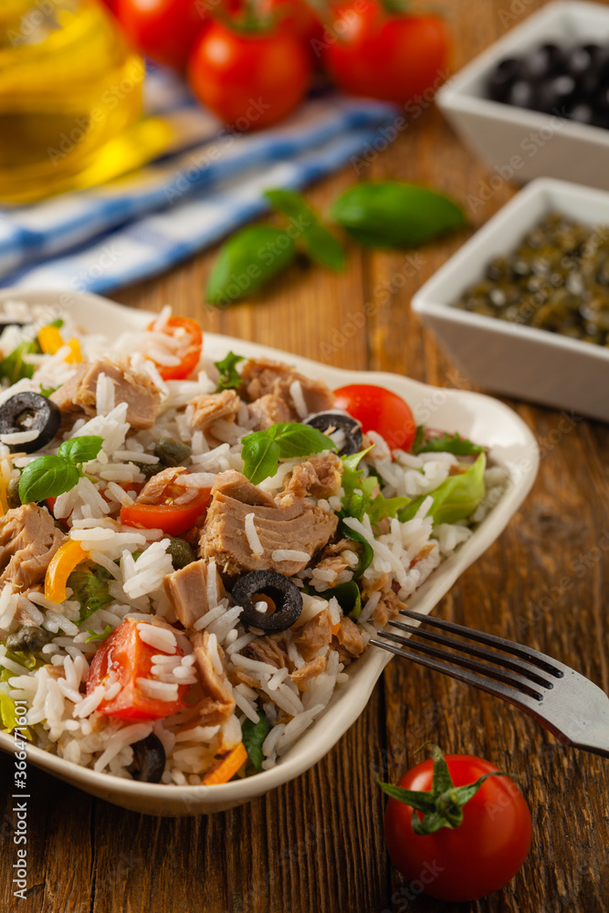 Italian tuna salad with rice, olives and capers. Front view. Natural wooden background. Italian tuna salad with rice, olives and capers. Front view. Natural wooden background.