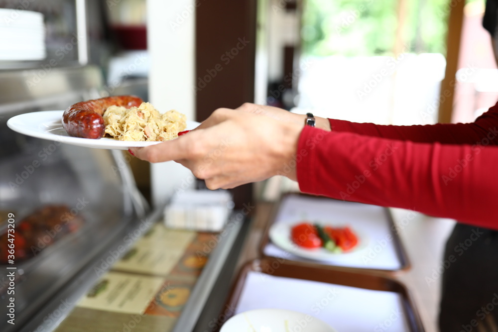 Woman is holding plate of food in bistro. Self service in cafes and restaurants concept