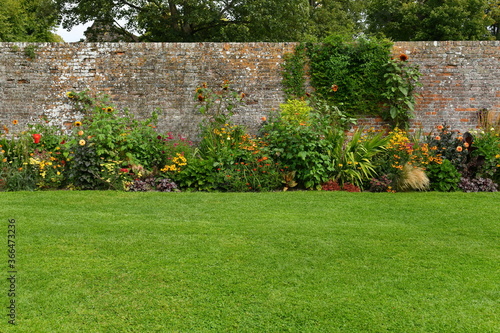 garden grass lawn, flower bed and old boundary wall