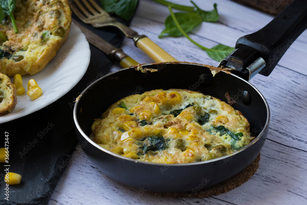 An omelette with sweet corn, green peas and spinach.