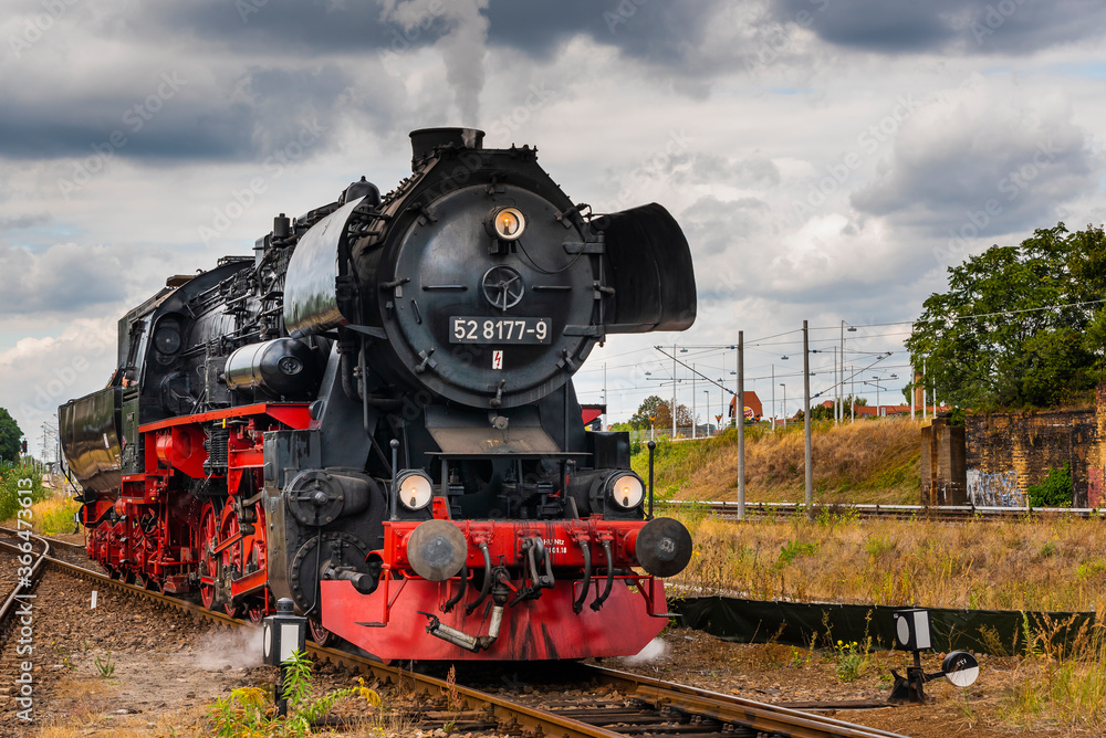 Naklejka premium Lokomotywa parowa, niemiecka lokomotywa parowa, lokomotywa parowa i duże chmury w tle