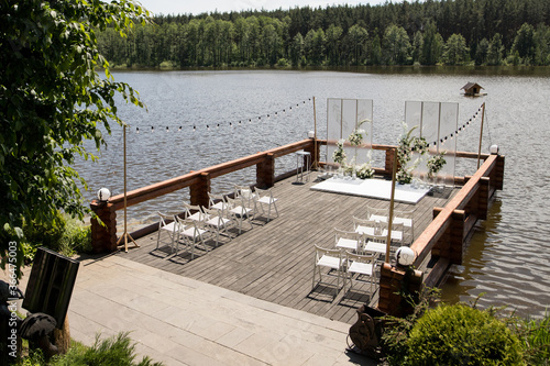 Beautiful wedding ceremony place on the lake with natural materials in white color