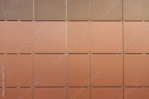 The wall is lined with colored ceramic tiles of brown color. Minimalism, background © Olga Makukha