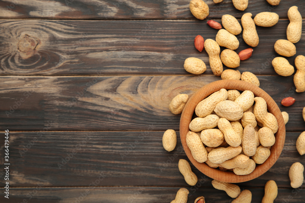 Dried peanuts in wooden bowl on brown wooden background. Dried peanuts in wooden bowl on brown wooden background.