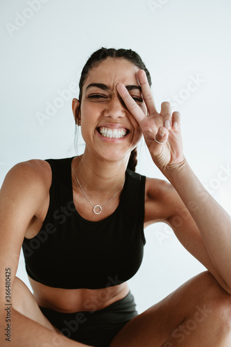Fototapeta Naklejka Na Ścianę i Meble -  Cheerful fitness woman with peace sign