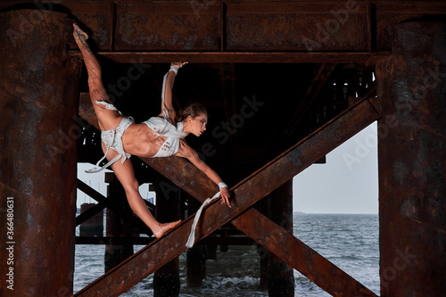 girl does gymnastic stunt on iron bridge