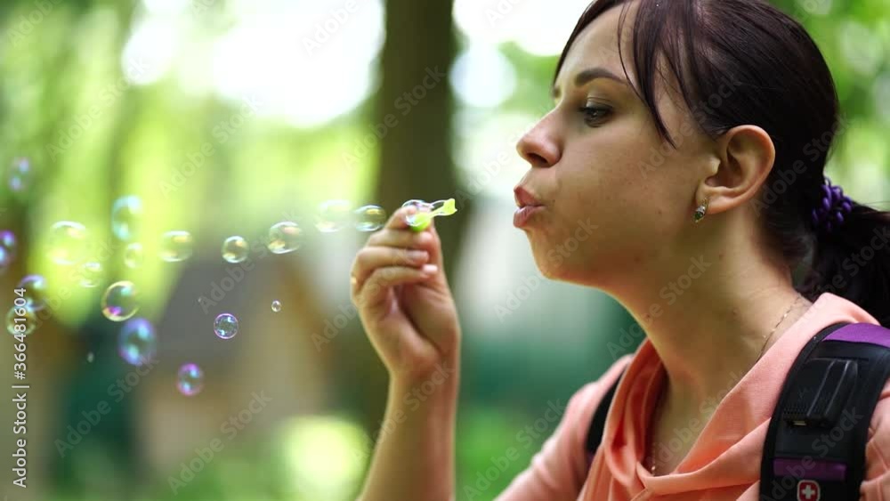 Young woman blowing bubbles on nature. Happy young brunette woman strolls in the Park and makes soap bubbles on a Sunny day Young woman blowing bubbles on nature. Happy young brunette woman strolls in the Park and makes soap bubbles on a Sunny day