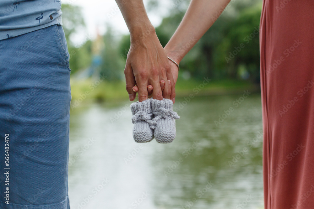 Mother and father (man and woman) are holding hand-knitted baby booties Mother and father (man and woman) are holding hand-knitted baby booties