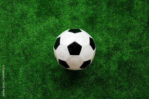 Soccer ball on green grass background top view copy space