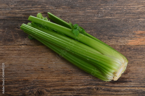 Bunch of fresh celery stalk with leaves on old wooden background photo