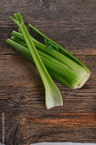 Bunch of fresh celery stalk with leaves on old wooden background
