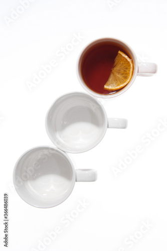 Cup with tea and lemon and emty cups isolated on white background