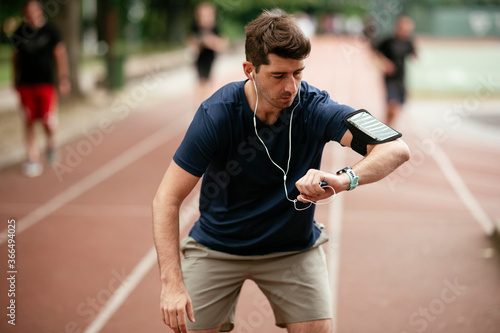 Young man checking his heart rate during work out. Young man exercising on the athletics track  © JustLife