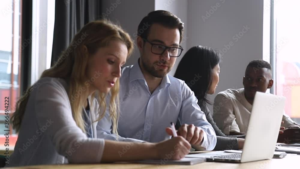 Helpful experienced male boss mentor teacher instructing young female intern trainee new worker making notes explaining new online project looking at laptop computer at apprentice course in office Helpful experienced male boss mentor teacher instructing young female intern trainee new worker making notes explaining new online project looking at laptop computer at apprentice course in office