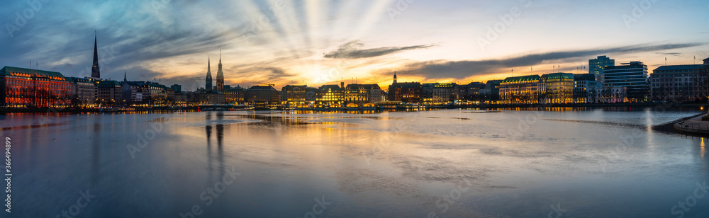 panoramic view of Alster Lake and cityscape in Hamburg, Germany during sunset against dramatic sky