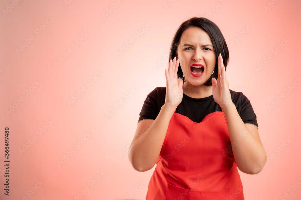 Woman employed at supermarket with red apron and black t-shirt shouting with her hands to her mouth Woman employed at supermarket with red apron and black t-shirt shouting with her hands to her mouth