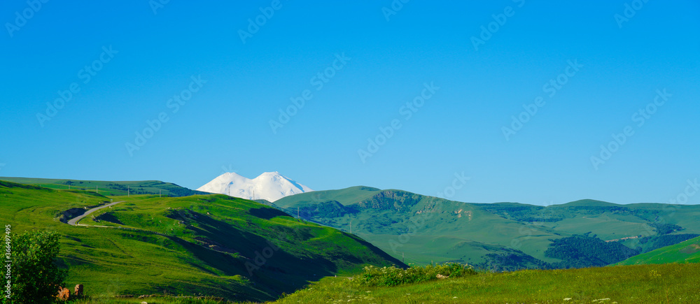 Elbrus and Green Meadow Hills at a Summer Day. Panorama