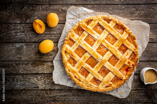 Summer apricot or peach pie homemade on wooden background, top view. Delicious fruit dessert. Fruit cake. Copy space.