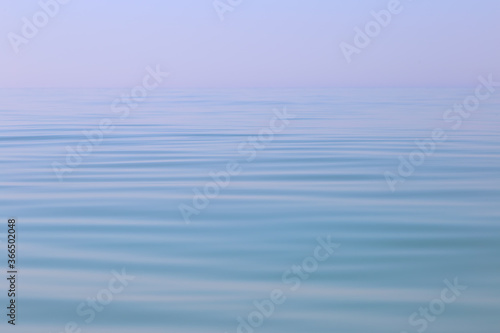 Calm sea wavy surface of the sea under a clear sky close-up. Blue background.