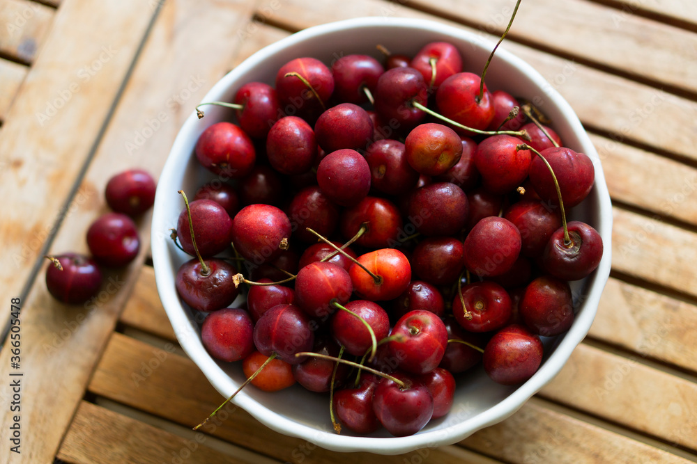 Cherries on wooden table with white porcelain bowl. Cherries on wooden table with white porcelain bowl.