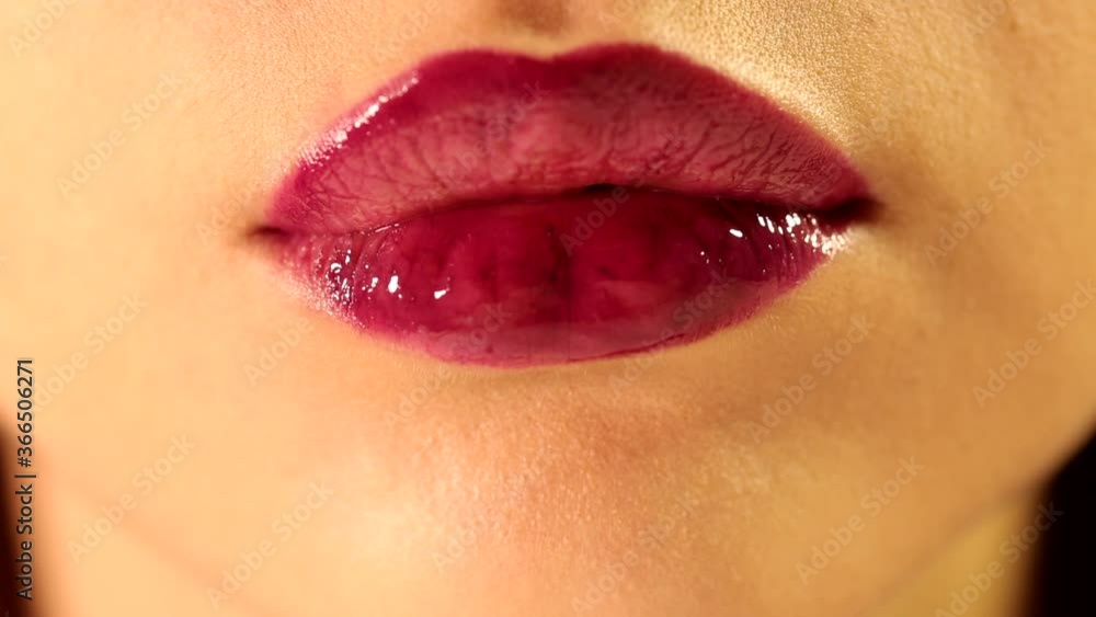 Beautiful female tongue licking her lips with bright deep red plum berry glossy lipstick tint lipgloss in close up shot Beautiful female tongue licking her lips with bright deep red plum berry glossy lipstick tint lipgloss in close up shot