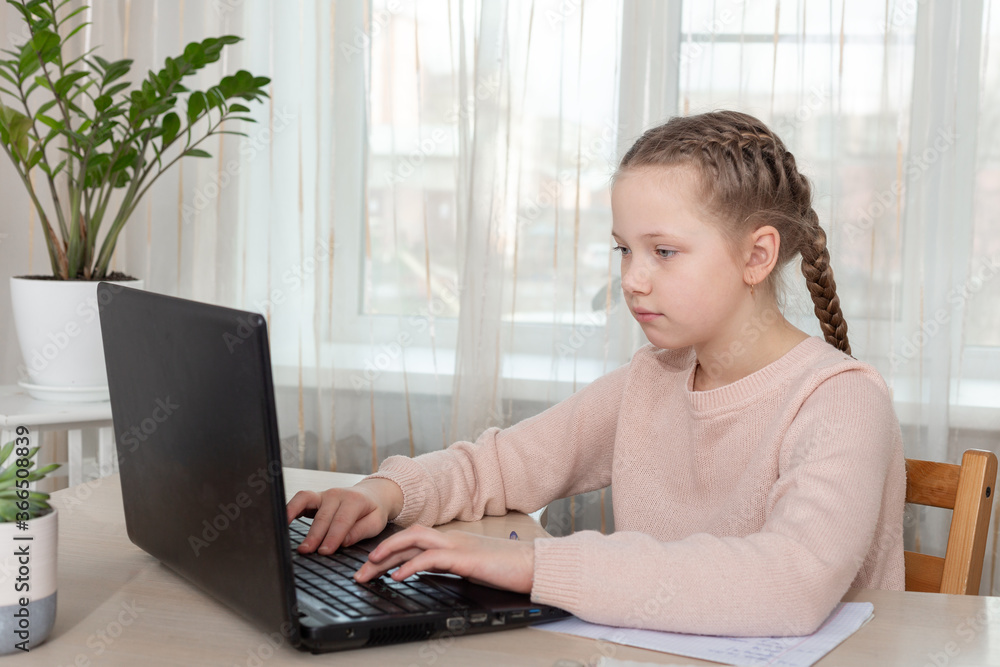 Schoolgirl studying at home. Young girl using laptop at home. Distance and home education concept Schoolgirl studying at home. Young girl using laptop at home. Distance and home education concept