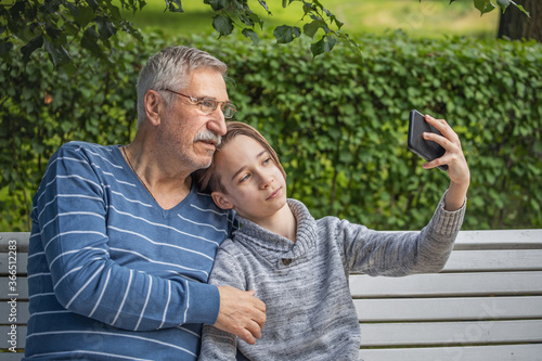 portrait of a boy and grandfather, happy, cheerful grandfather and grandson with smartphone taking selfie at summer park, Leisure concept, school summer holidays © Leka
