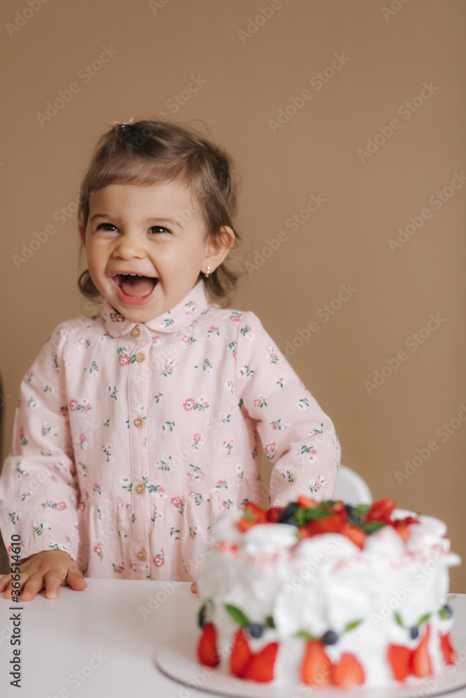 Cute little girl one and a hulf year old stand by delicious birthday cake. Eighteen month old girl verry happy and laughs. Vegetarian food. Lactose free and gluten free. Cute little girl one and a hulf year old stand by delicious birthday cake. Eighteen month old girl verry happy and laughs. Vegetarian food. Lactose free and gluten free.