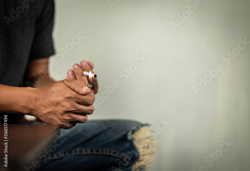 man sit on table and lighting a cigarette behind the wall. concept for narcotic, illness , crime.