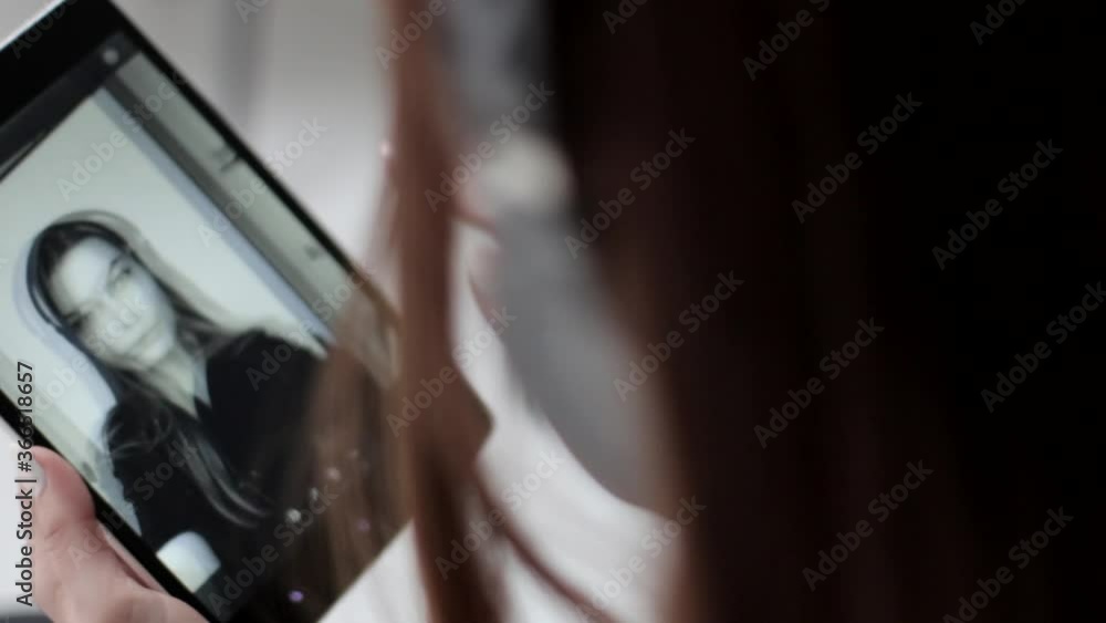 Pretty young lady watches her back and white selfie photographs and deletes them on multi touch tablet Pretty young lady watches her back and white selfie photographs and deletes them on multi touch tablet