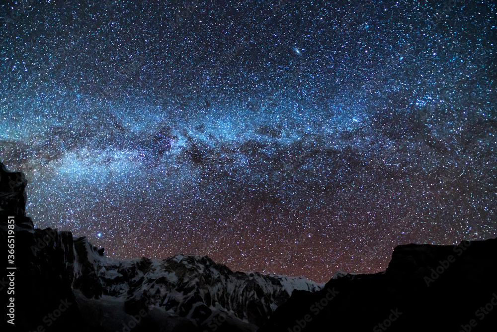 Milky Way and mountains. Amazing scene with Himalayan mountains and starry sky at night in Nepal. Rocks with snowy peak and sky with stars. Annapurna Range. Night landscape with bright milky way