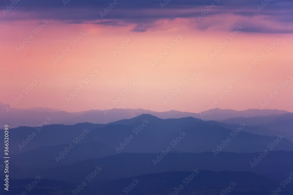 Silhouettes of mountains the evening light with haze in the atmosphere, perspective aerial view.