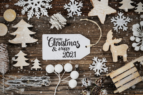 One White Label With English Text Merry Christmas And A Happy 2021. Frame Of Christmas Decoration Like Tree, Sled, Star And Fir Cone. Wooden Background With Snowflakes