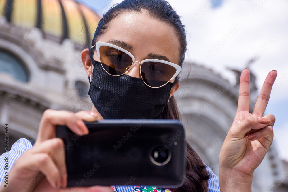 woman with face mask takes a selfie on the street 