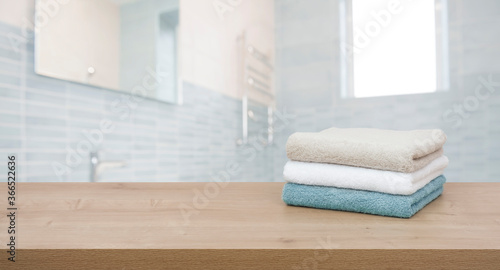 Cotton towels on wooden table in blurred bathroom interior background