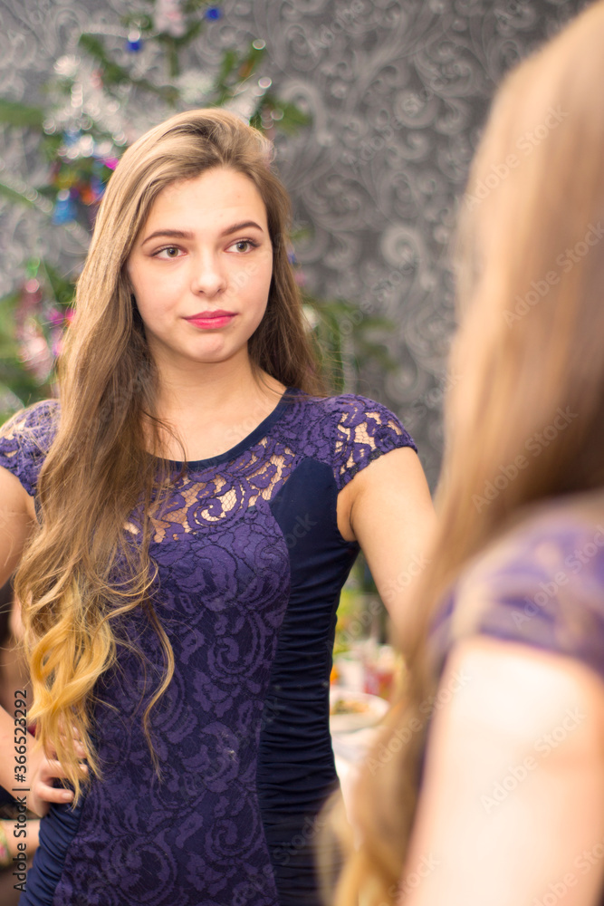 Naklejka premium The girl picks up a dress looking in the mirror.