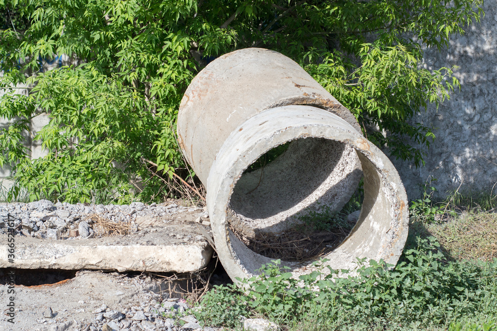 Massive concrete rings lay on green grass. Parts of a well Massive concrete rings lay on green grass. Parts of a well