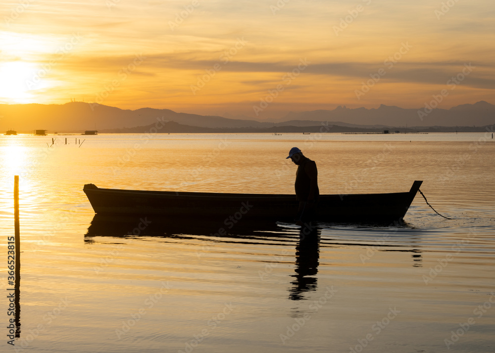 silhouette of a fisherman and his canoe at sunset
