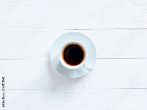 Top view of white cup of black coffee or hot chocolate on a shabby white board wooden table. Flat lay lifestyle, copy space. Good morning concept.