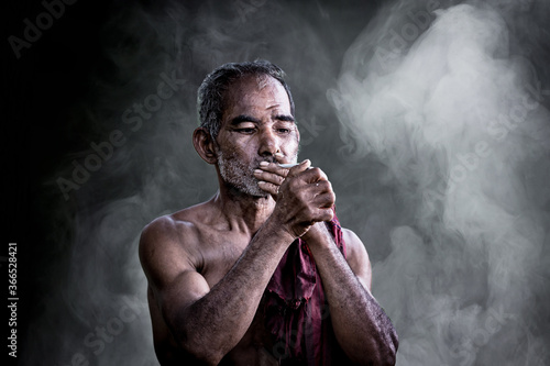 Vászonkép Asian old man smoking cigarette and the smoke released from the mouth against da