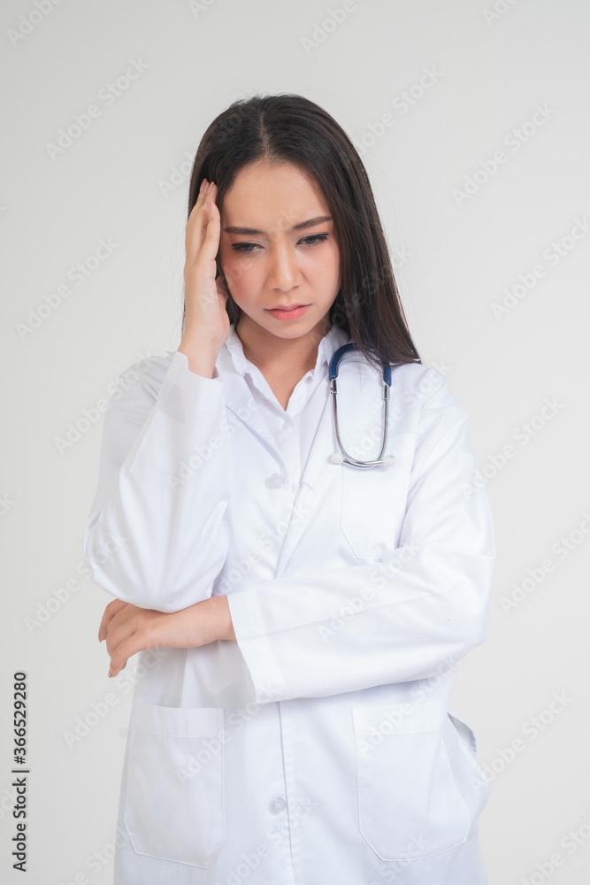 Young Asian woman doctor standing and holding hands in the head Due to headache, she looks unhappy and tired because of overwork, Concept of stressed and doctor liability, Dealing with frustrated Young Asian woman doctor standing and holding hands in the head Due to headache, she looks unhappy and tired because of overwork, Concept of stressed and doctor liability, Dealing with frustrated