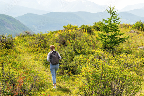 Woman with rucksack hiking in the summer landscape. Hiker with backpack in mountains.
