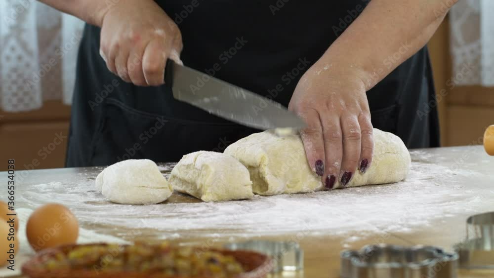 Close-up women's hands cut dough with knife baking pastry at home, housewife preparing pie cake or handmade cookies on table sprinkled with flour. DIY bakery concept Close-up women's hands cut dough with knife baking pastry at home, housewife preparing pie cake or handmade cookies on table sprinkled with flour. DIY bakery concept