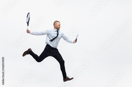 Time for movement. Man in office clothes plays tennis isolated on white studio background. Businessman training in motion, action. Unusual look for sportsman, new activity. Sport, healthy lifestyle.