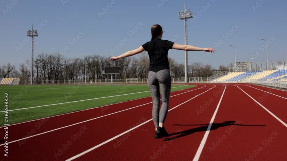 Attractive fit active young girl walking doing squats warming up stretching muscles outdoor working out at big stadium Attractive fit active young girl walking doing squats warming up stretching muscles outdoor working out at big stadium