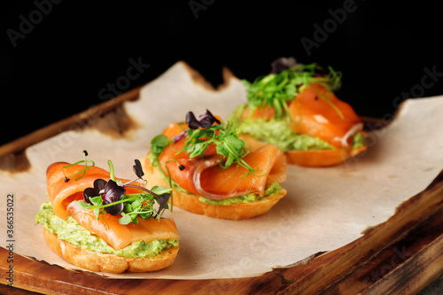 Selection of tasty bruschetta or canapes with salmon closeup. salmon tapas with guacamole and topped microgreen