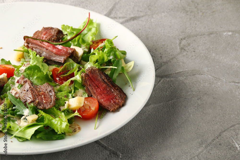 steak salad. Grilled Steak with Mixed Greed Salad cherry tomatoes and parmesan with fresh sauce in white plate on concrete background steak salad. Grilled Steak with Mixed Greed Salad cherry tomatoes and parmesan with fresh sauce in white plate on concrete background