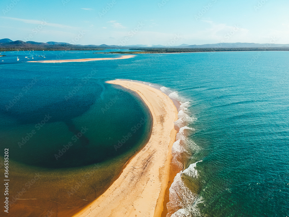 Waves hitting a sand bank in the middle of the water of Bustard Bay off the coast of Australia