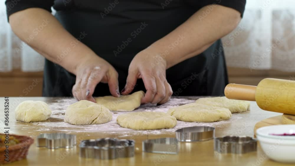 Close-up women's hands knead dough baking pastry at home, preparing pizza or handmade danish cookies. DIY bakery, baking moulds and rolling pin on table sprinkled with flour. Close-up women's hands knead dough baking pastry at home, preparing pizza or handmade danish cookies. DIY bakery, baking moulds and rolling pin on table sprinkled with flour.