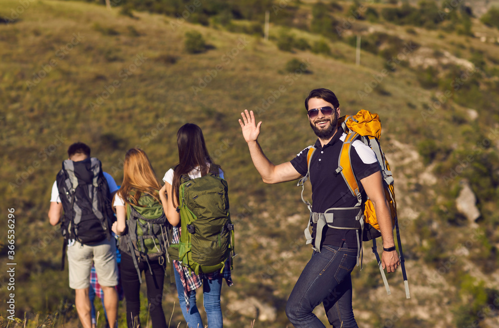 A group of hikers with backpacks are walking along the hill in the mountains in nature.